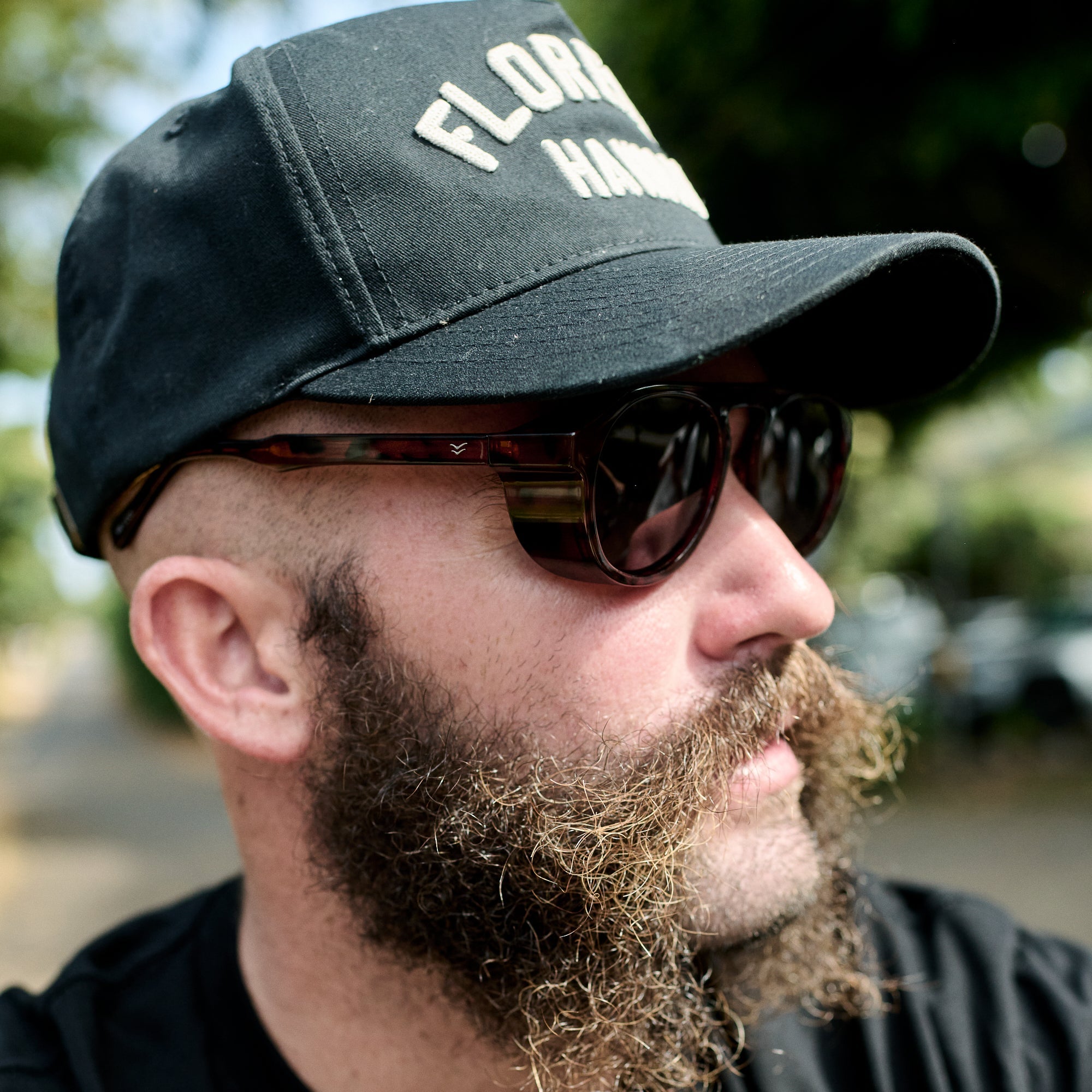 Man wearing a black cap with 'Florida' text and sunglasses, outdoors.