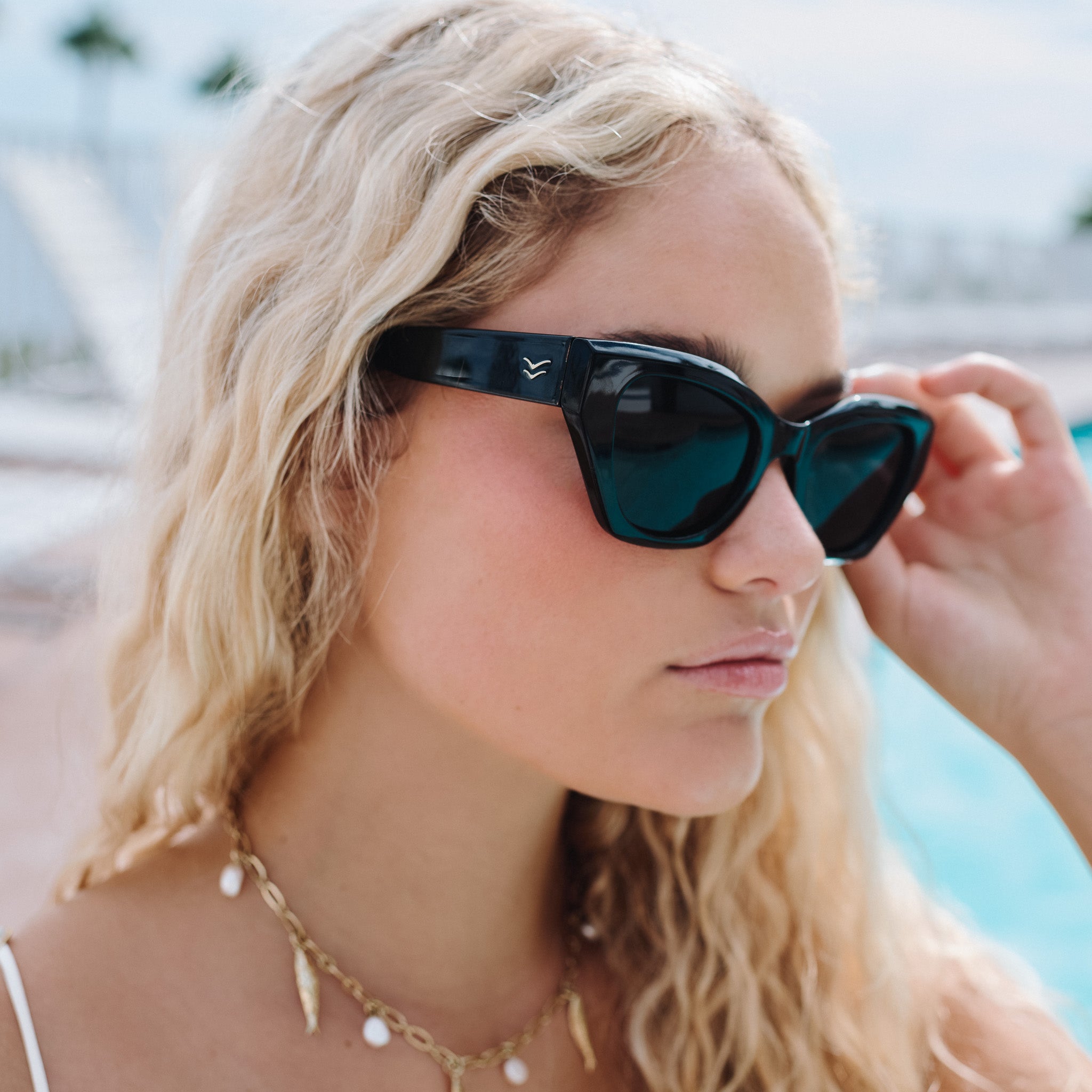 Woman wearing dark sunglasses with a blurred outdoor background.
BLACK / SMOKE POLARIZED LENS