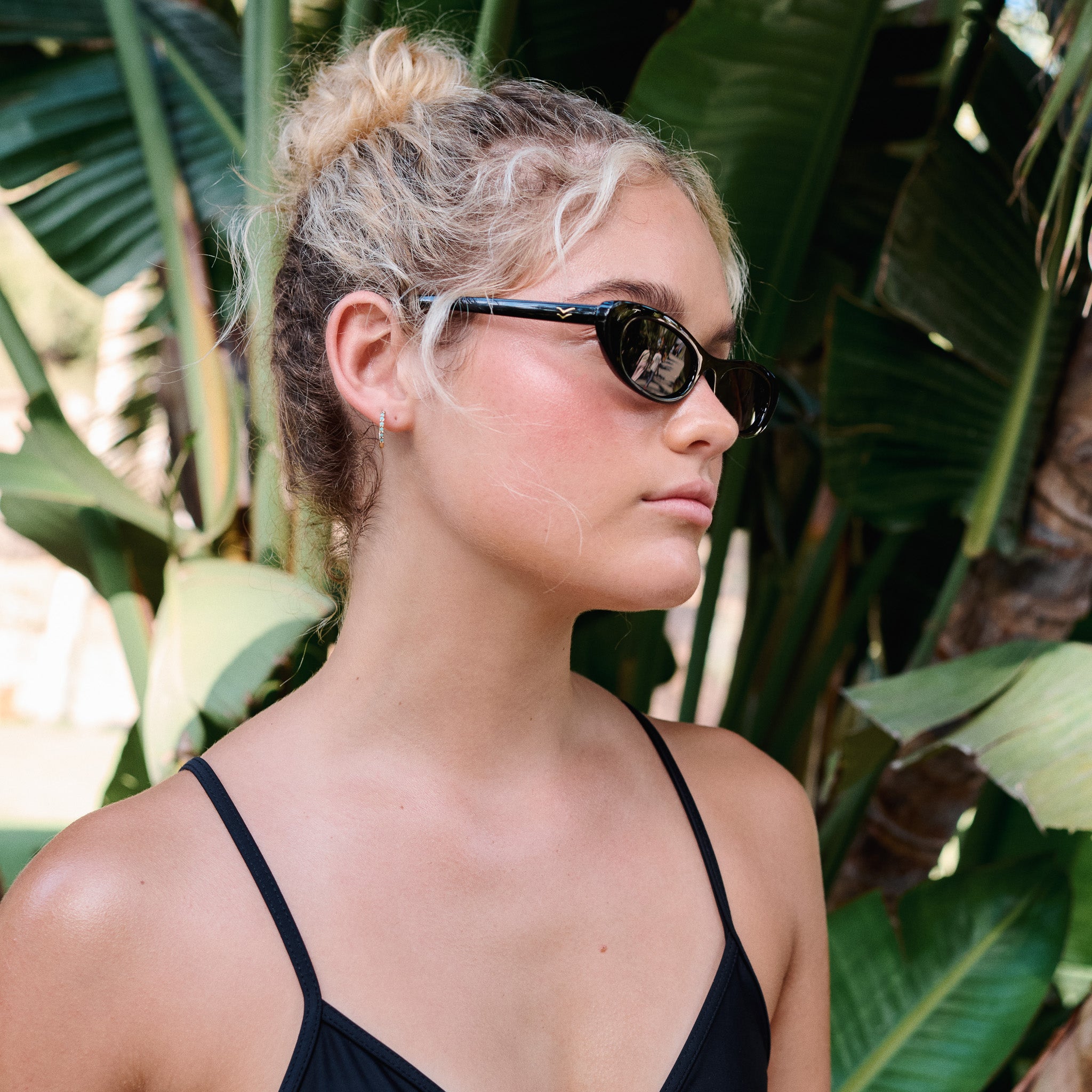 Woman wearing sunglasses with a tropical plant background.
BLACK / SMOKE POLARIZED LENS