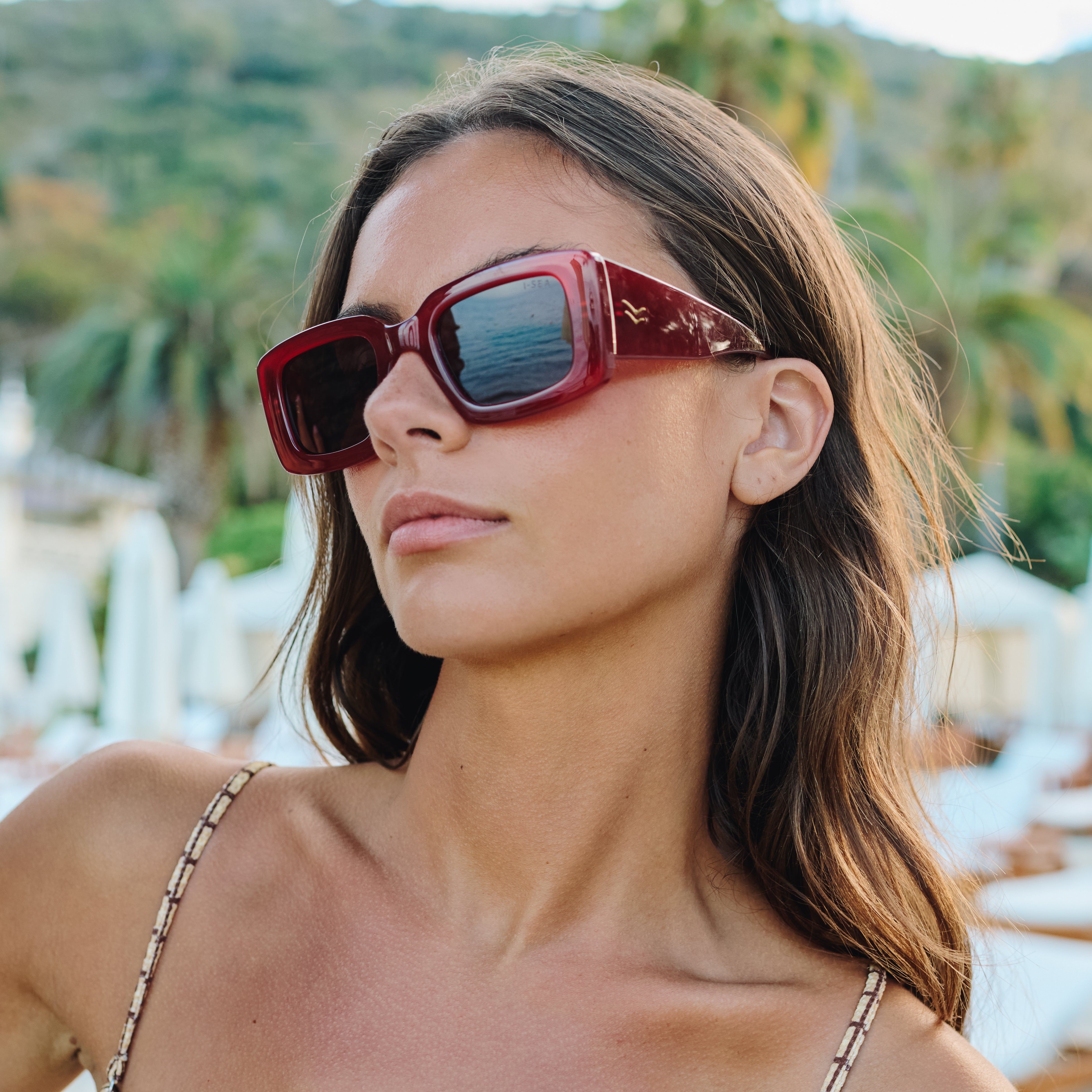Woman wearing red sunglasses with a blurred outdoor background.
RASPBERRY / PLUM POLARIZED LENS