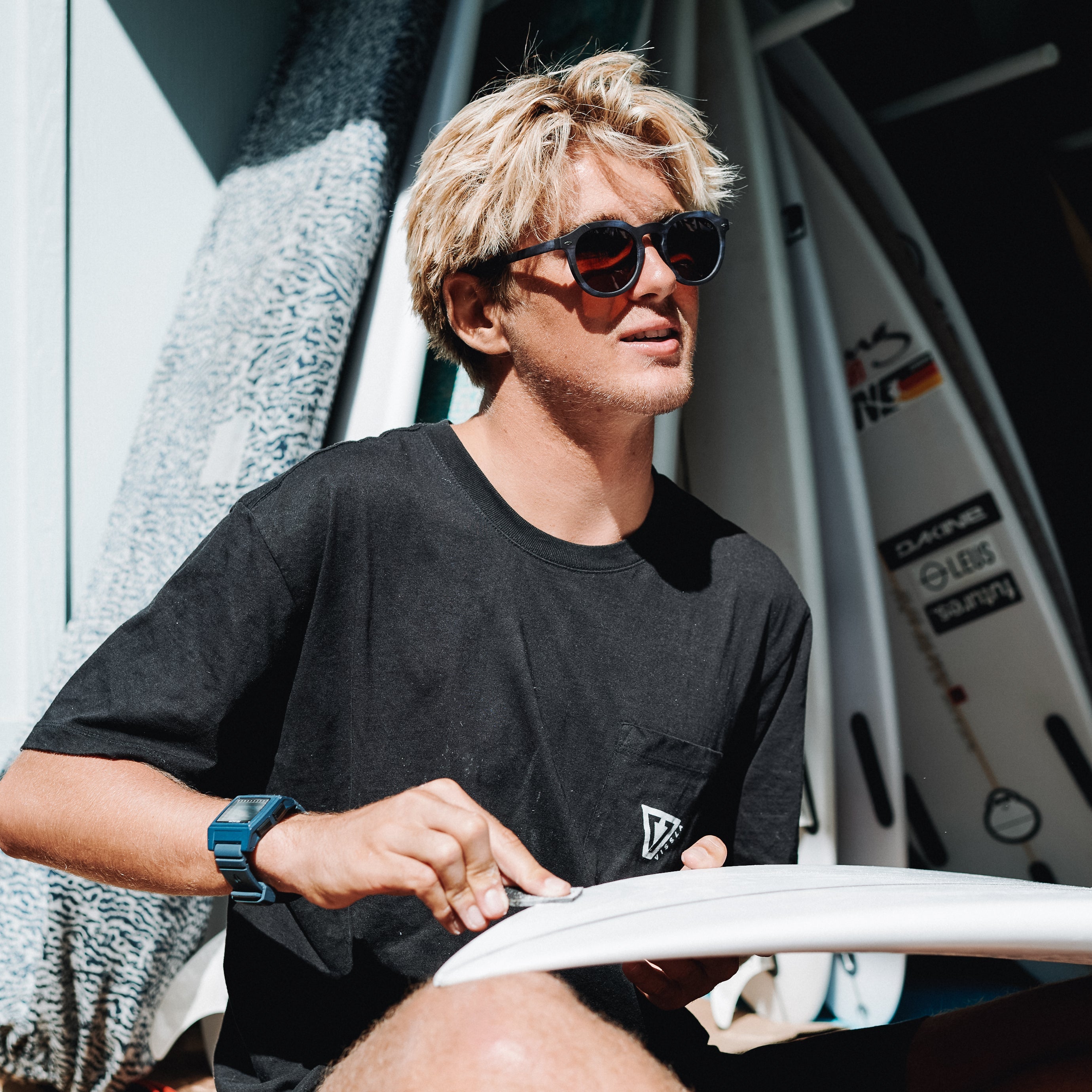 Man wearing sunglasses and a black t-shirt with surfboards in the background.
BLUE / BROWN POLARIZED LENS