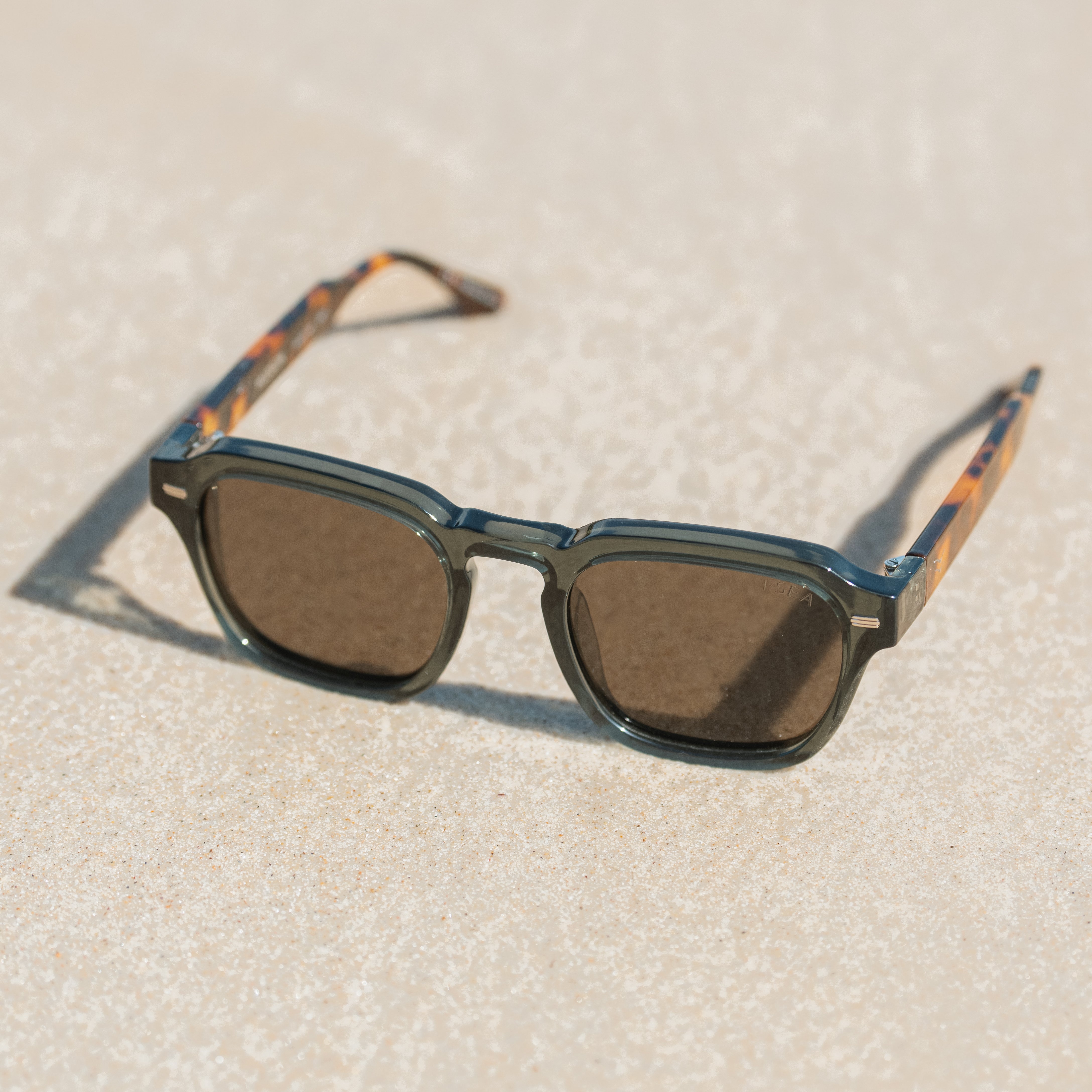 Sunglasses with colorful arm designs on a sandy surface.
LEAF & TORT / TAUPE POLARIZED LENS