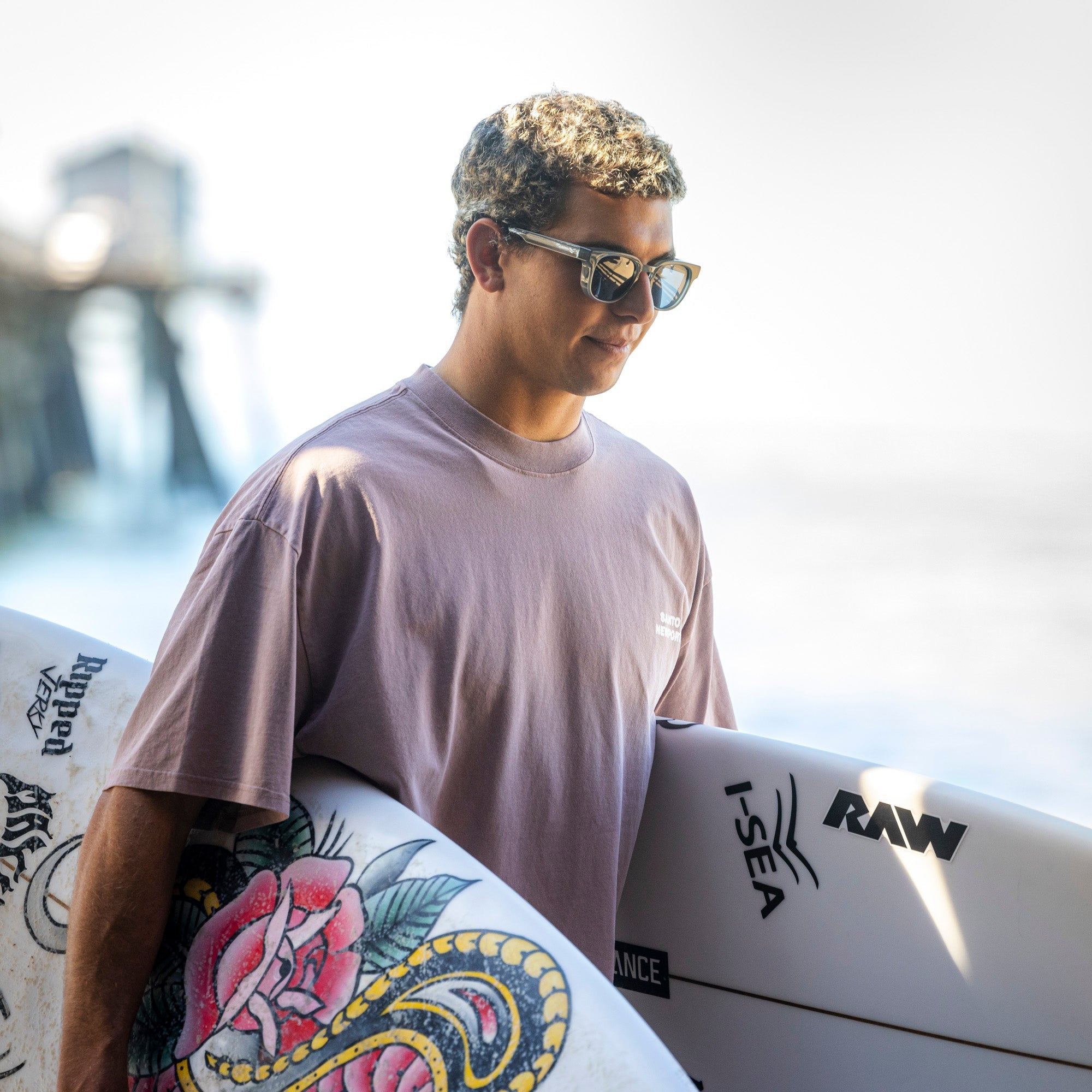 Man holding a surfboard with visible branding, standing outdoors.
GREY / NAVY POLARIZED LENS