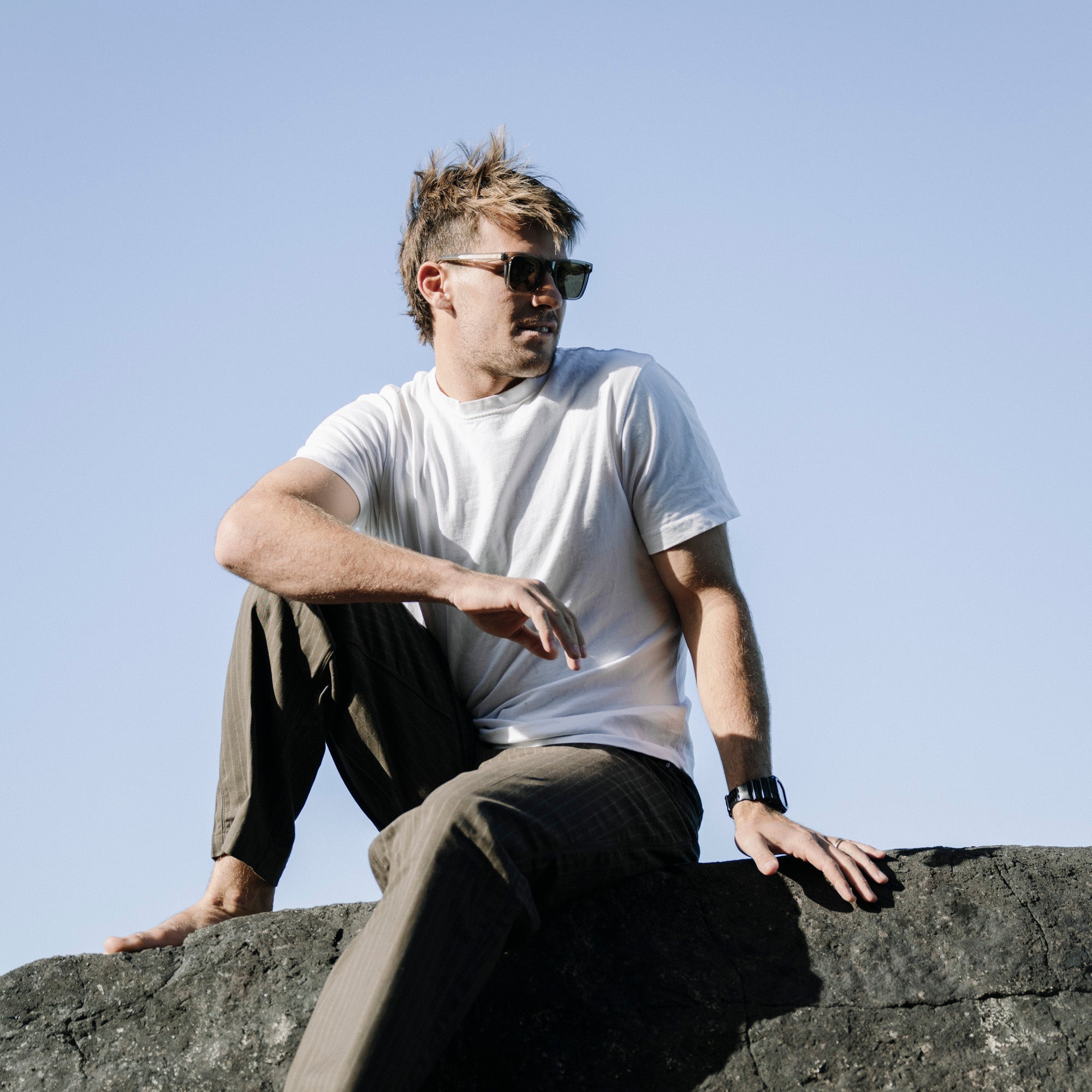 Man sitting on a rock with a clear blue sky background.
TAUPE / BROWN POLARIZED LENS