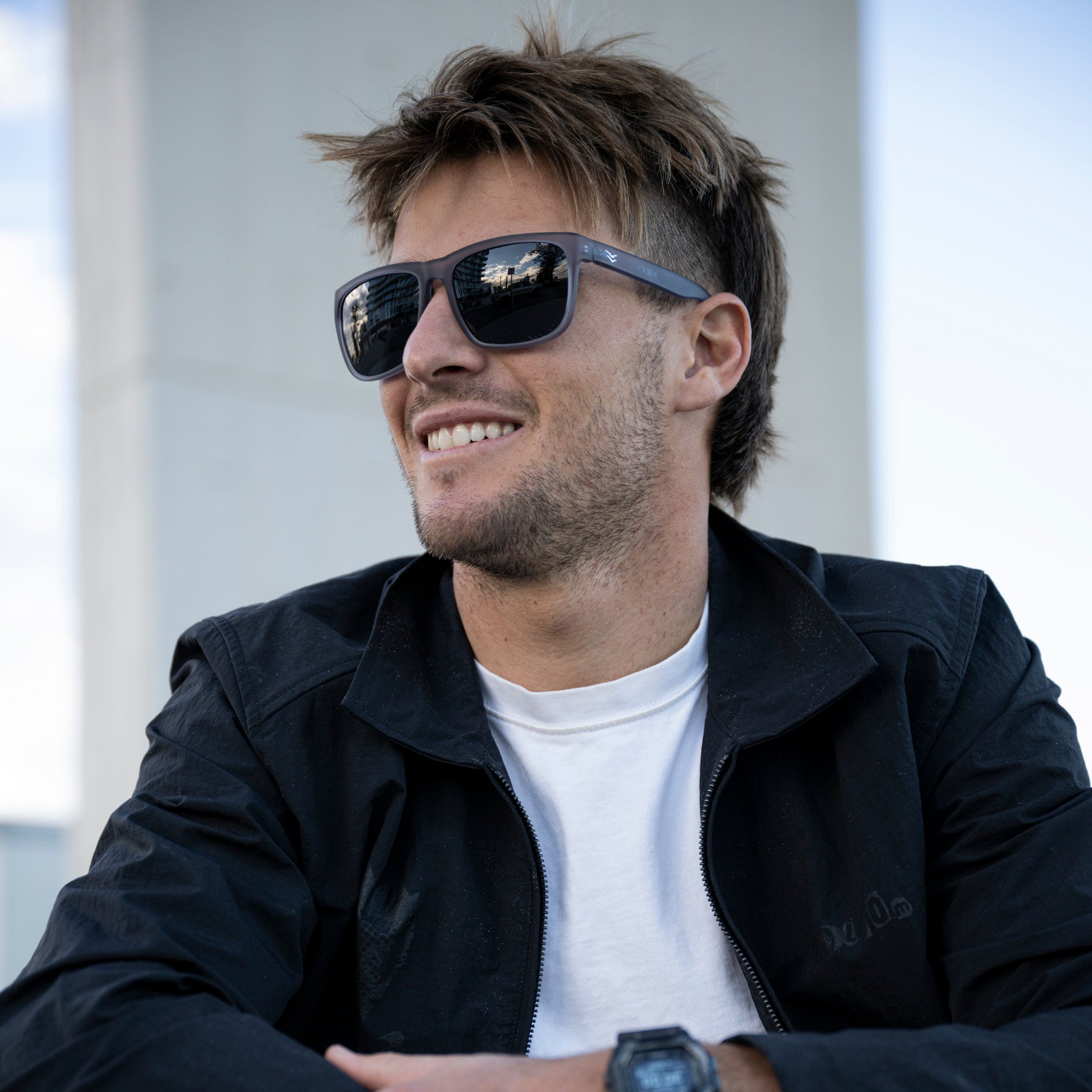 Man wearing sunglasses and a dark jacket with a blurred background.
GREY / SMOKE POLARIZED LENS