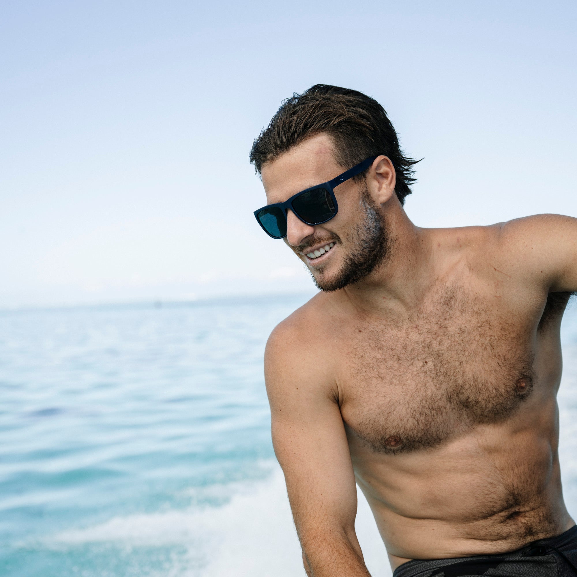 Man wearing sunglasses and no shirt by the ocean.
SEA / SMOKE POLARIZED LENS