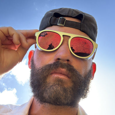 Man wearing reflective sunglasses with a clear blue sky background