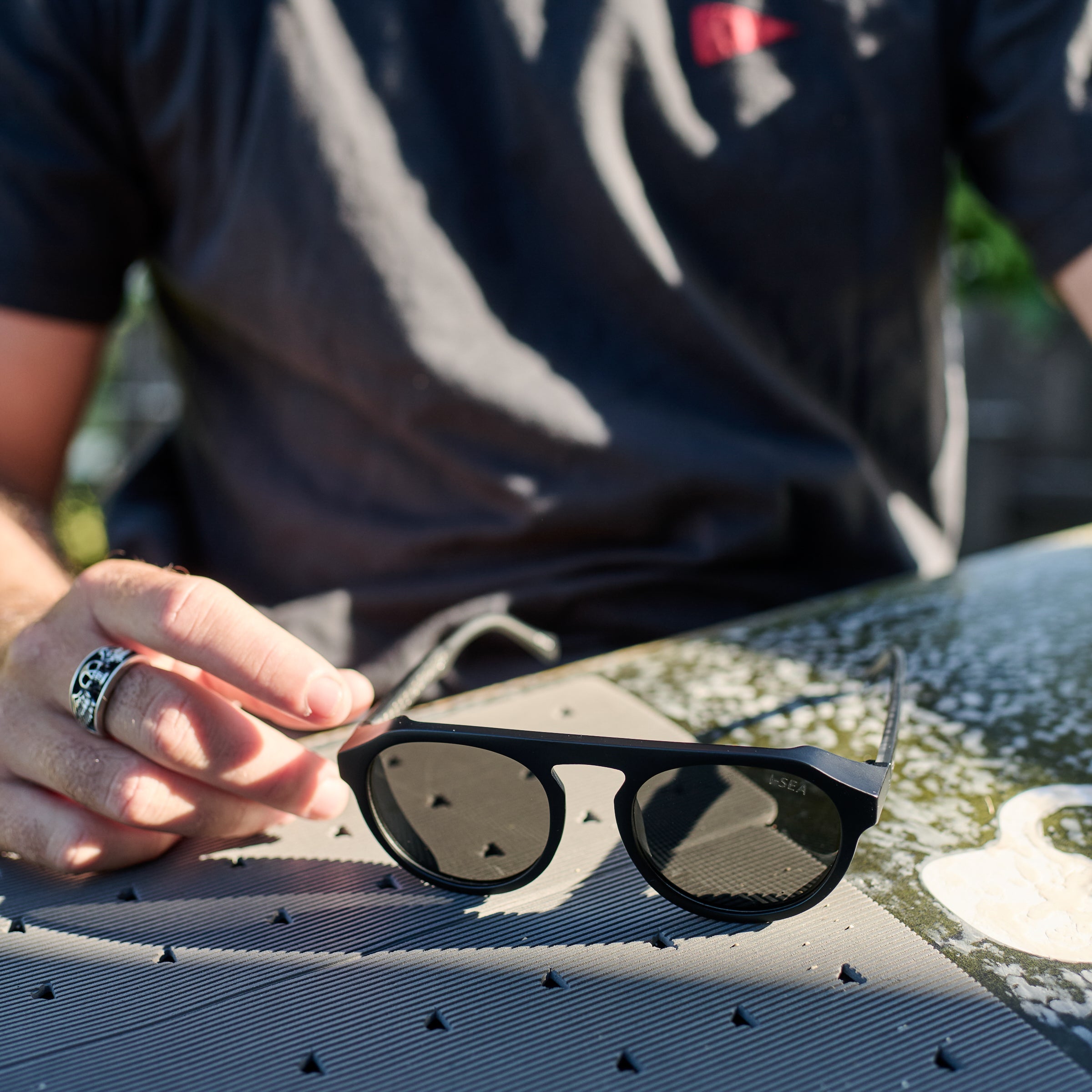 Person holding sunglasses on a textured surface with a blurred background