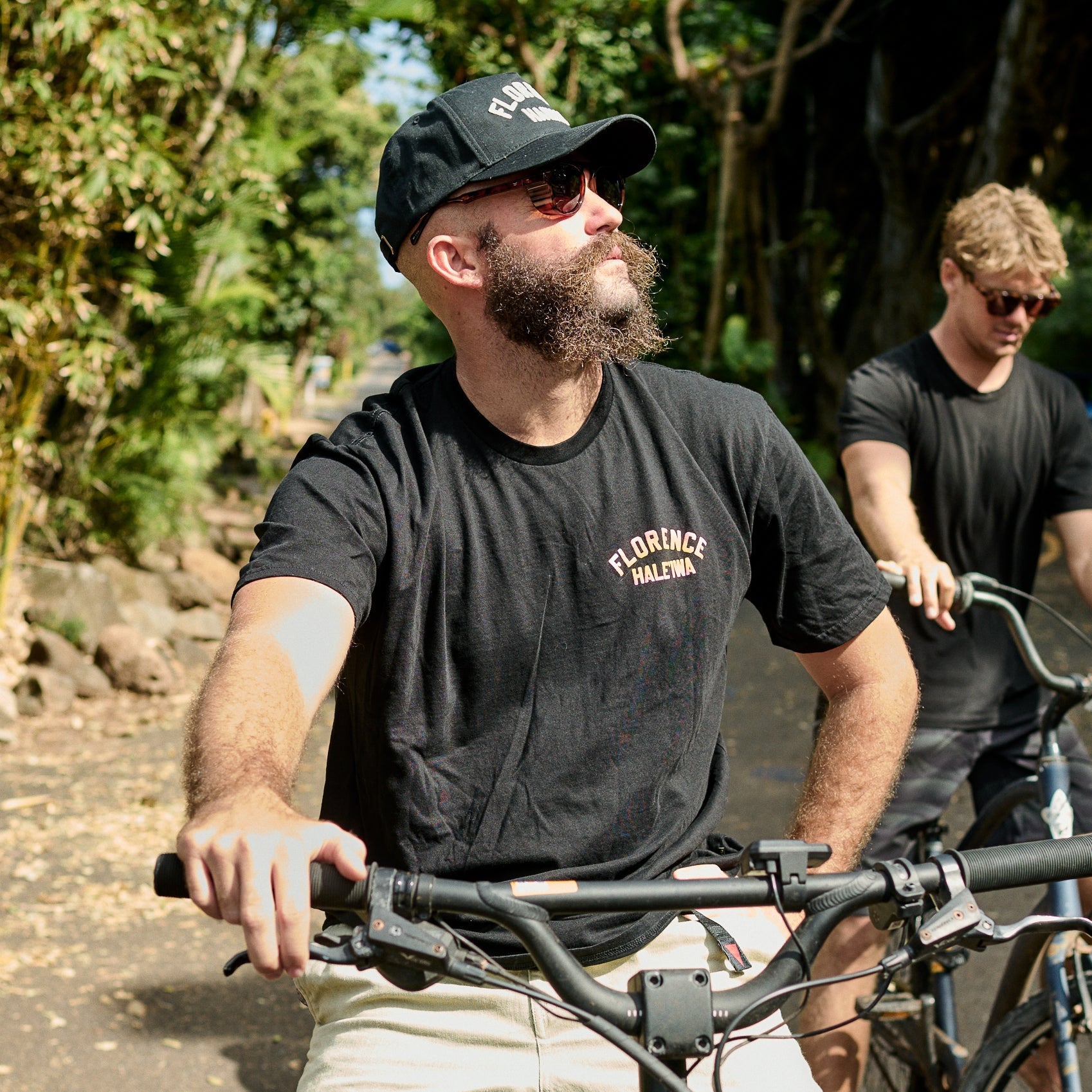 Two men riding bicycles on a path with trees in the background