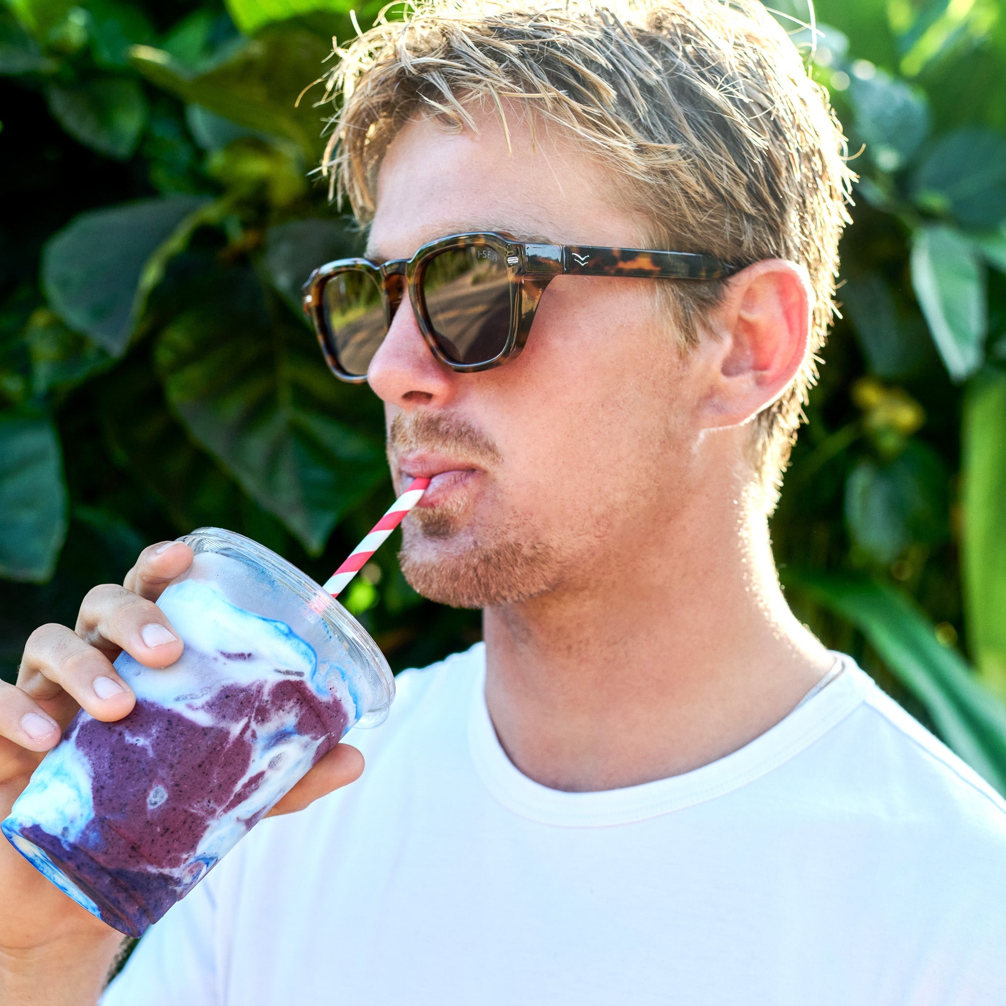 Man drinking a purple smoothie outdoors with sunglasses on.
TORT / BROWN POLARIZED LENS