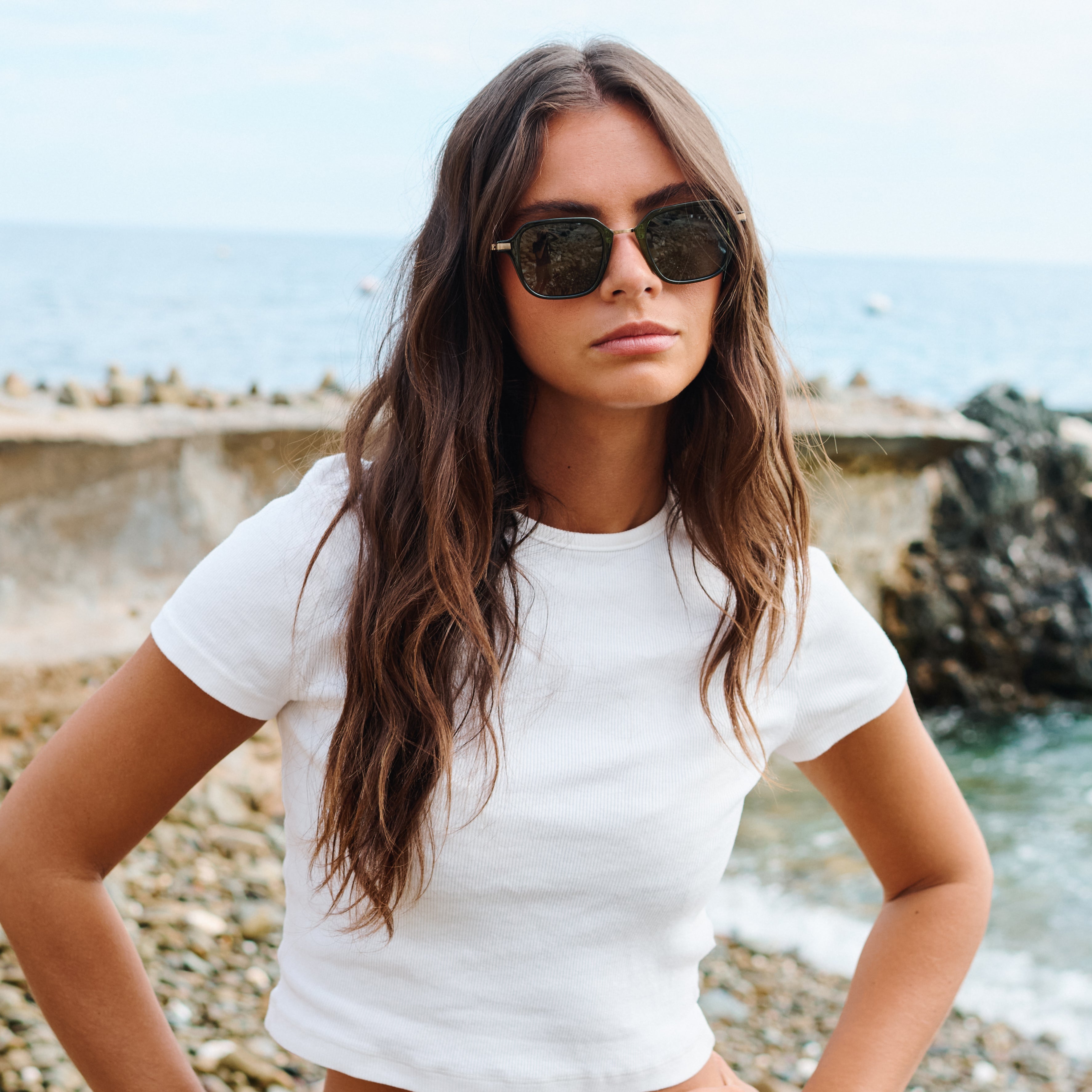 Woman wearing sunglasses and a white t-shirt by the sea. Color:
EMERALD / GREEN POLARIZED LENS