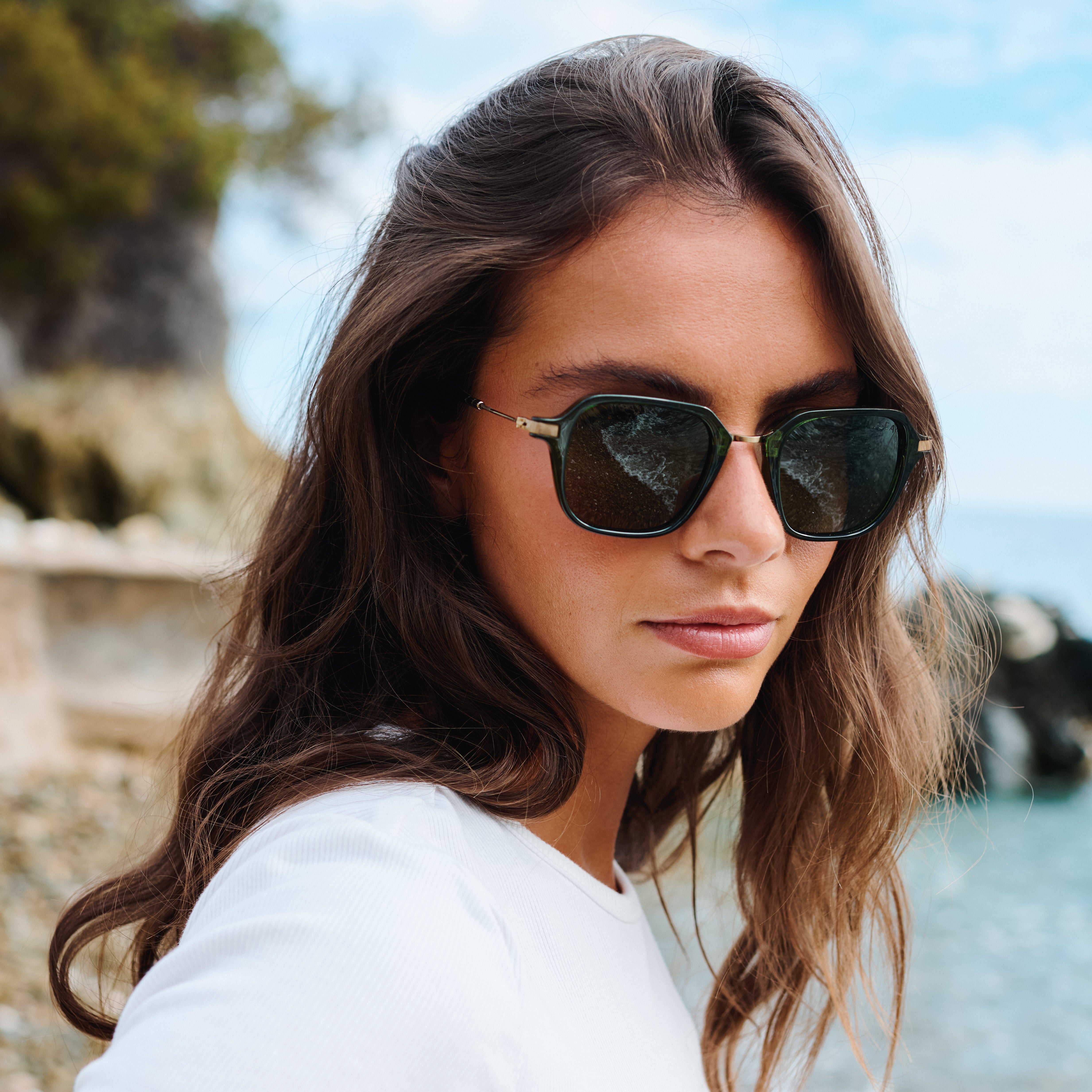 Woman wearing sunglasses with a blurred natural background. Color:
EMERALD / GREEN POLARIZED LENS