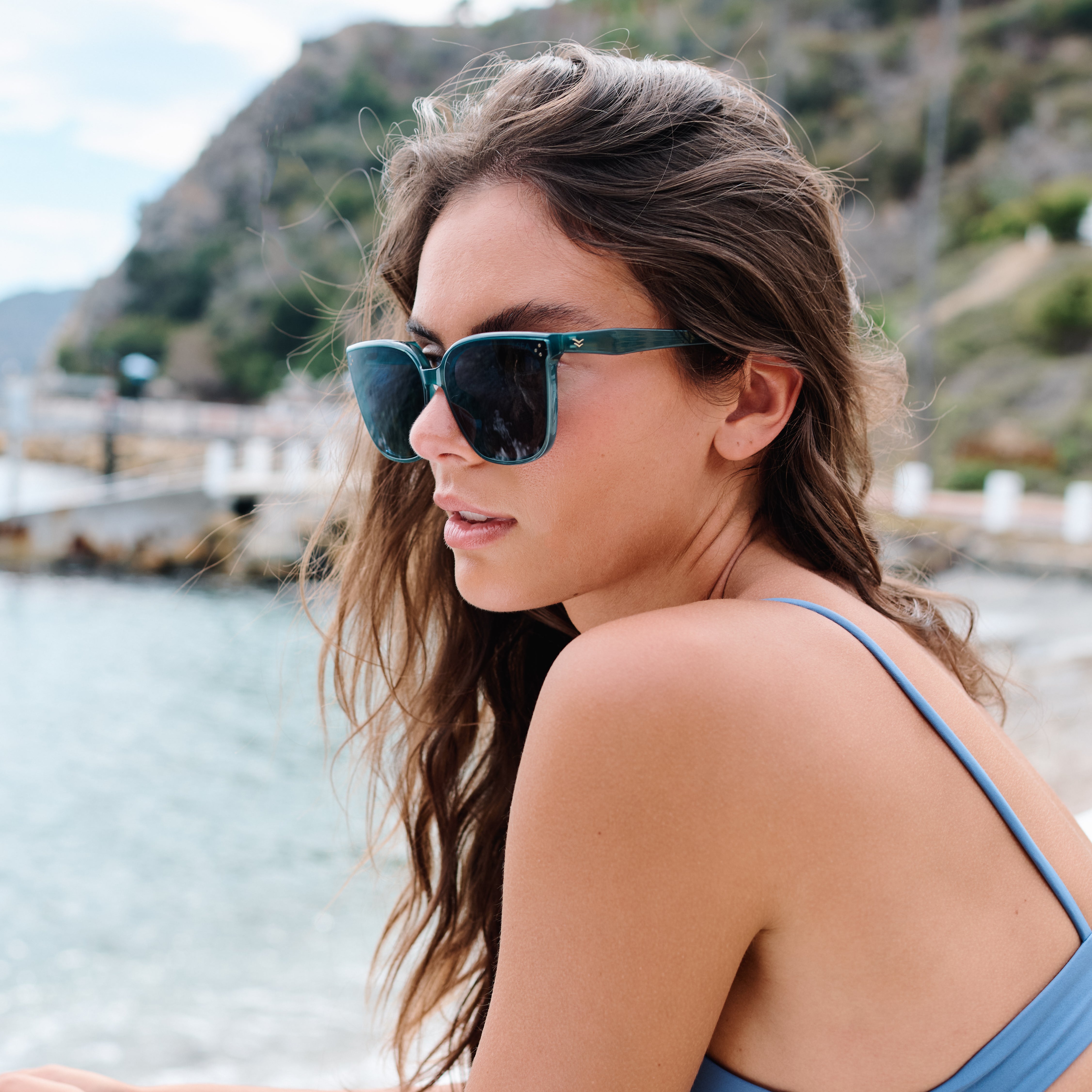 Woman wearing sunglasses with a scenic background of water and mountains.
POOL / NAVY POLARIZED LENS