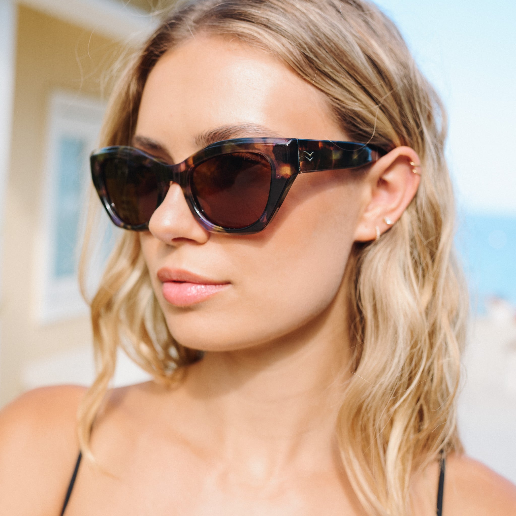 Woman wearing tortoiseshell sunglasses with a blurred outdoor background.
BLUE TORT / BROWN POLARIZED LENS