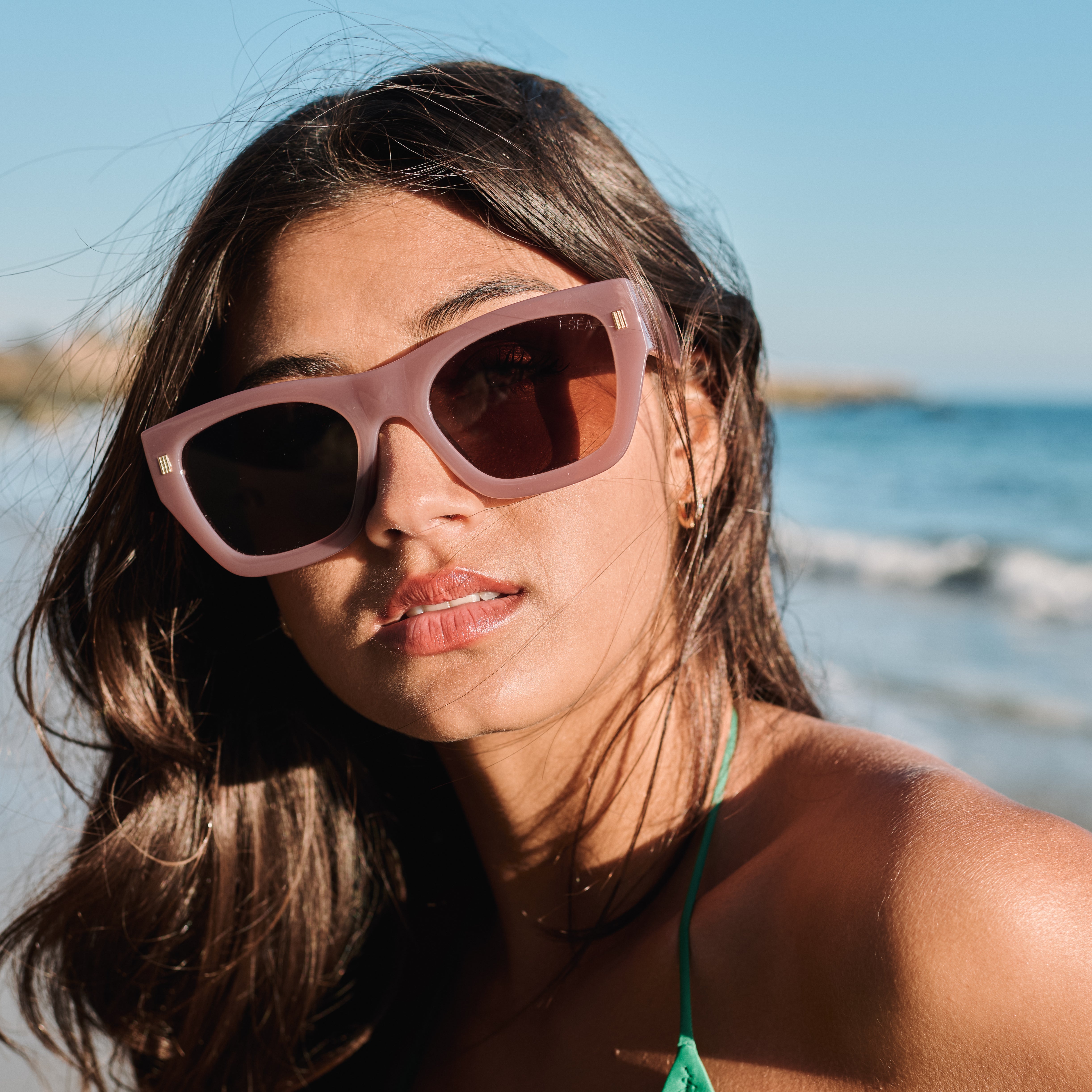 Woman wearing sunglasses with a beach background.
DUSTY ROSE / BROWN POLARIZED LENS