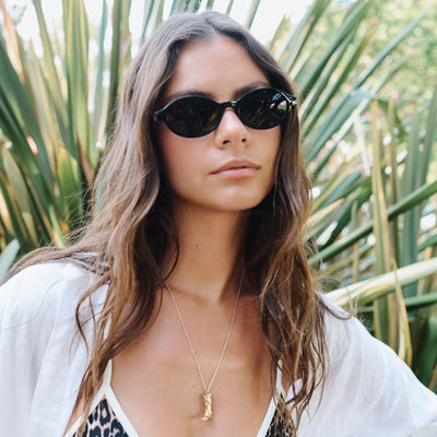 Woman wearing sunglasses with a tropical background.
BLACK / SMOKE POLARIZED LENS