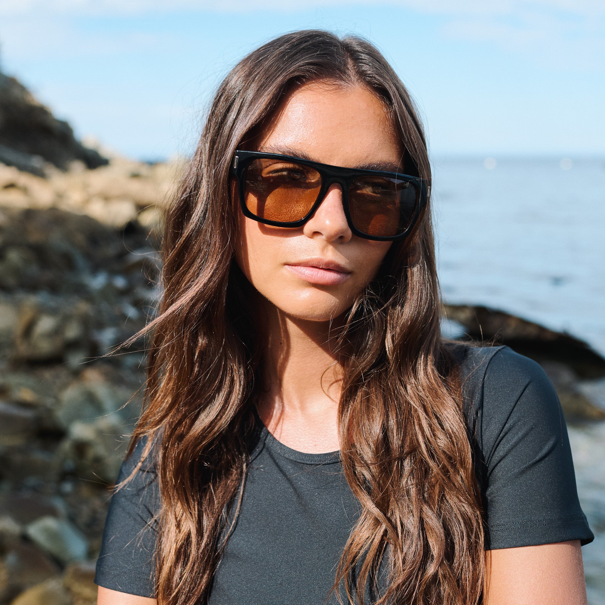 Woman wearing sunglasses with a coastal background.
COLA / BROWN POLARIZED LENS
