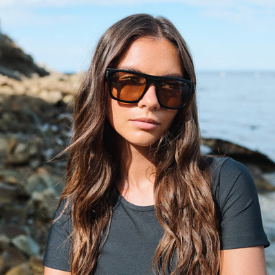 Woman wearing sunglasses with a coastal background.
COLA / BROWN POLARIZED LENS