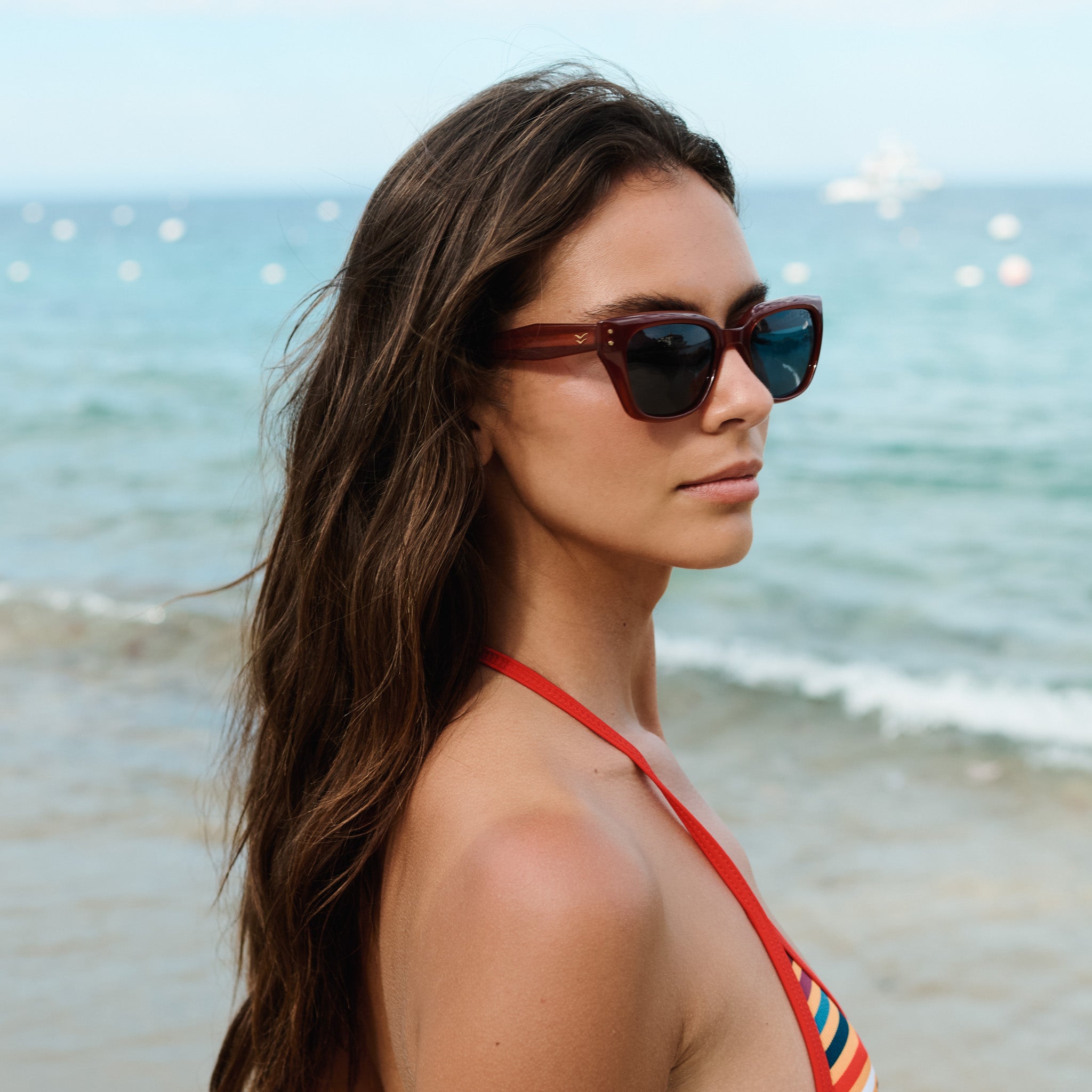Woman wearing sunglasses and a colorful bikini top on a beach.
GINGER / SKY POLARIZED LENS