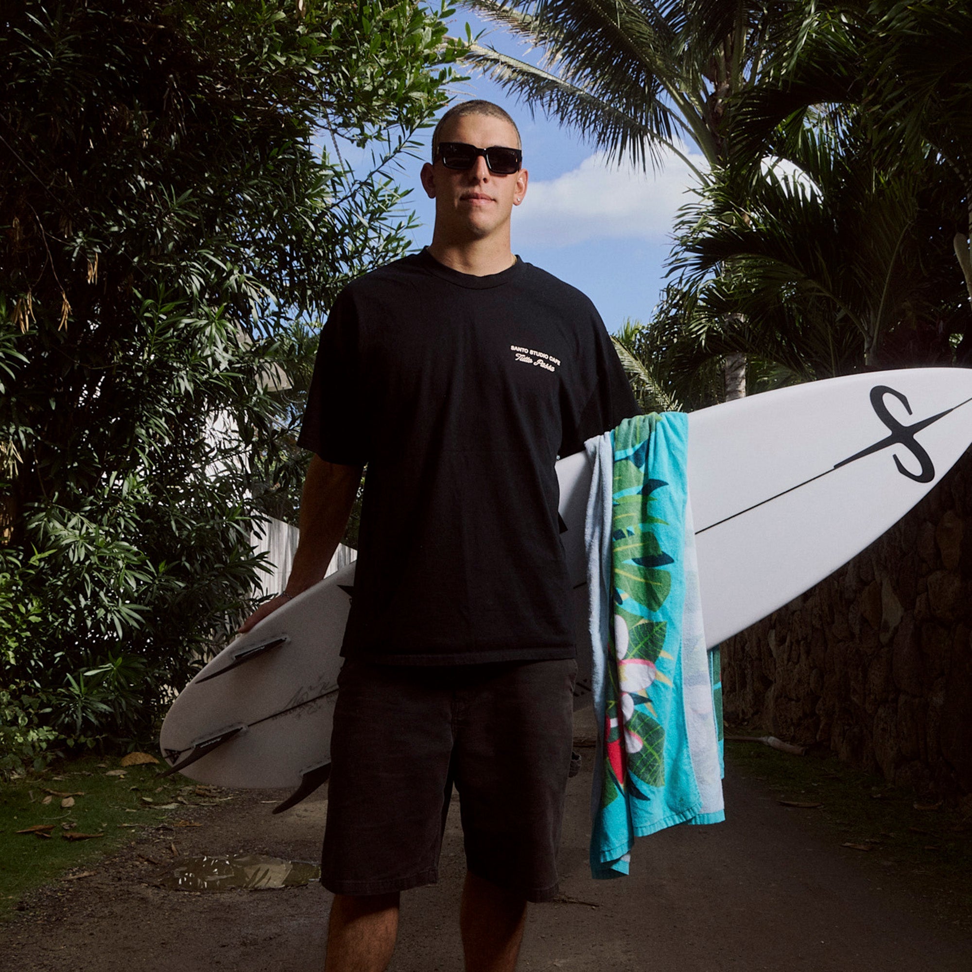 Man holding a surfboard with a towel draped over his shoulder, surrounded by greenery.
BLACK LEOPARD / SMOKE POLARIZED LENS