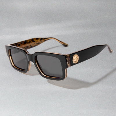 Sunglasses with tortoiseshell and gold accents on a light gray background.
BLACK LEOPARD / SMOKE POLARIZED LENS