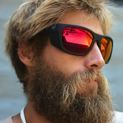 Man wearing sunglasses with a blurred background.
BLACK RUBBER / RED MIRROR POLARIZED LENS