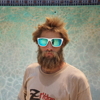 Man with a beard and sunglasses standing in front of a textured wall.
WHITE RUBBER / BLUE MIRROR POLARIZED LENS