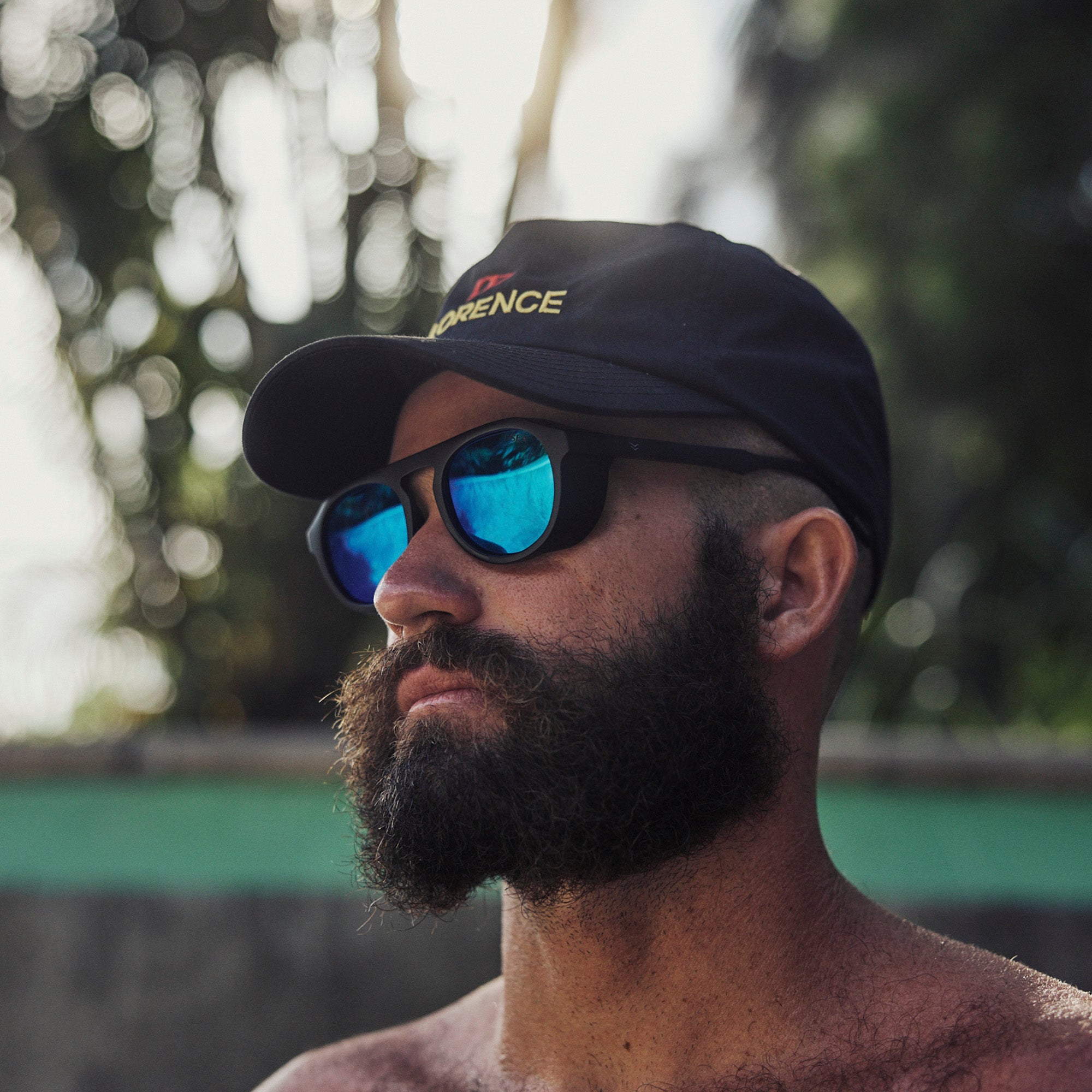 Man wearing a cap and sunglasses with a blurred natural background