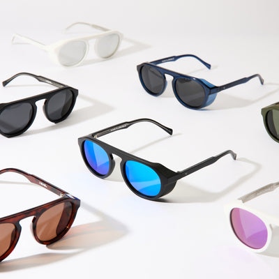 Collection of sunglasses with different lens colors and frames on a light background