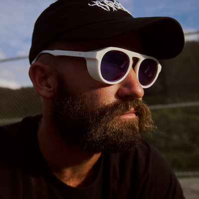 Man wearing a black cap and white sunglasses with a blurred background