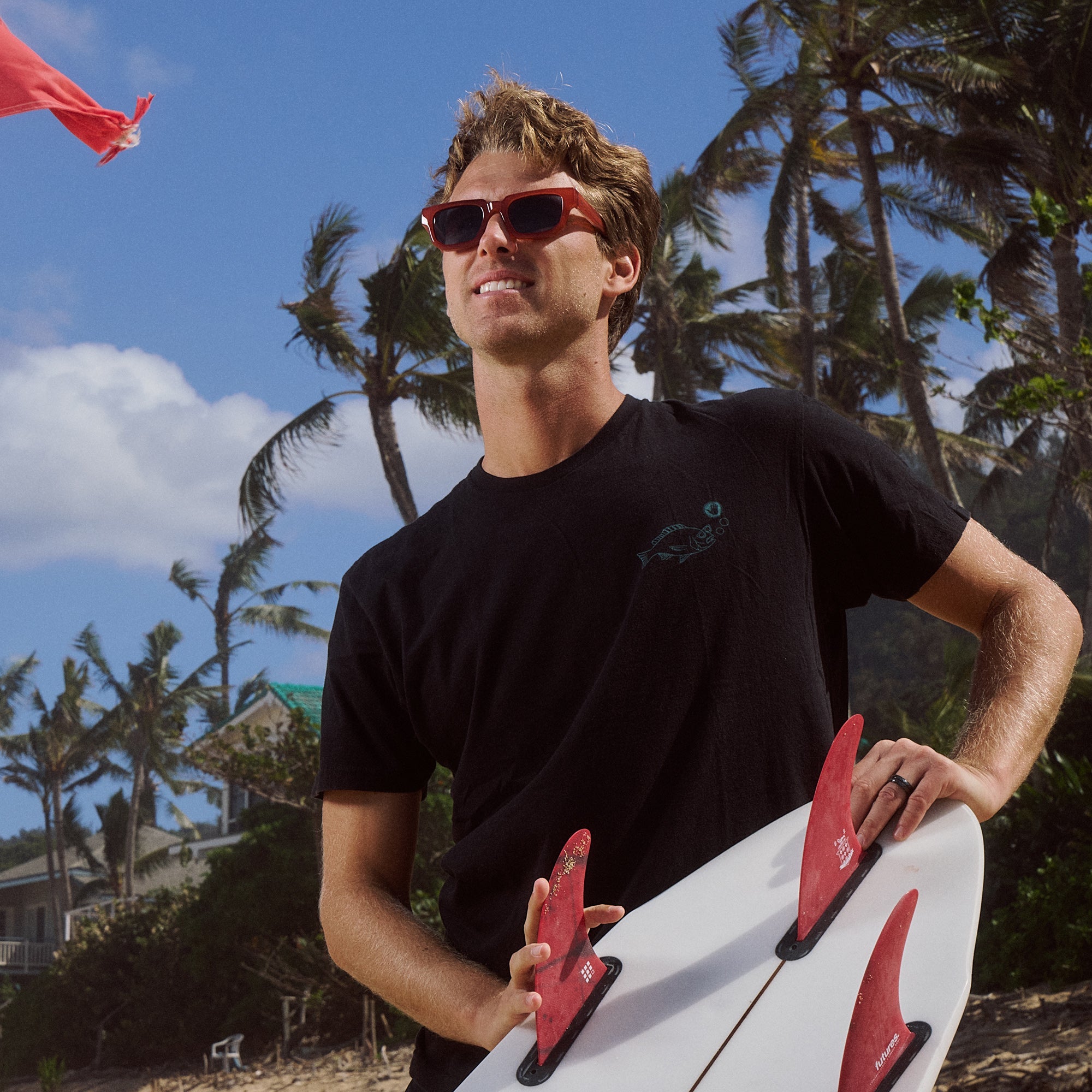Man holding a surfboard with palm trees and a clear sky in the background.
TANGERINE / NAVY POLARIZED LENS