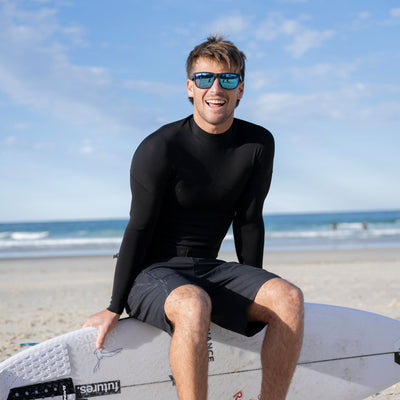 Man in a black wetsuit sitting on a surfboard at the beach.
BLACK / ICE BLUE POLARIZED LENS