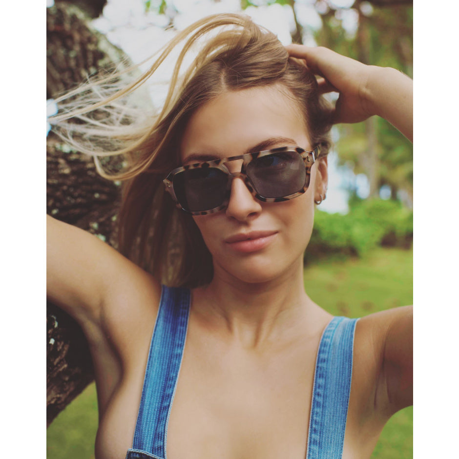 Woman wearing sunglasses and a blue top outdoors.
SNOW TORT / NAVY POLARIZED LENS