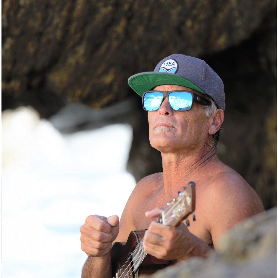 Man playing guitar on a beach with sunglasses and a cap.
BLACK / BLUE POLARIZED LENS
